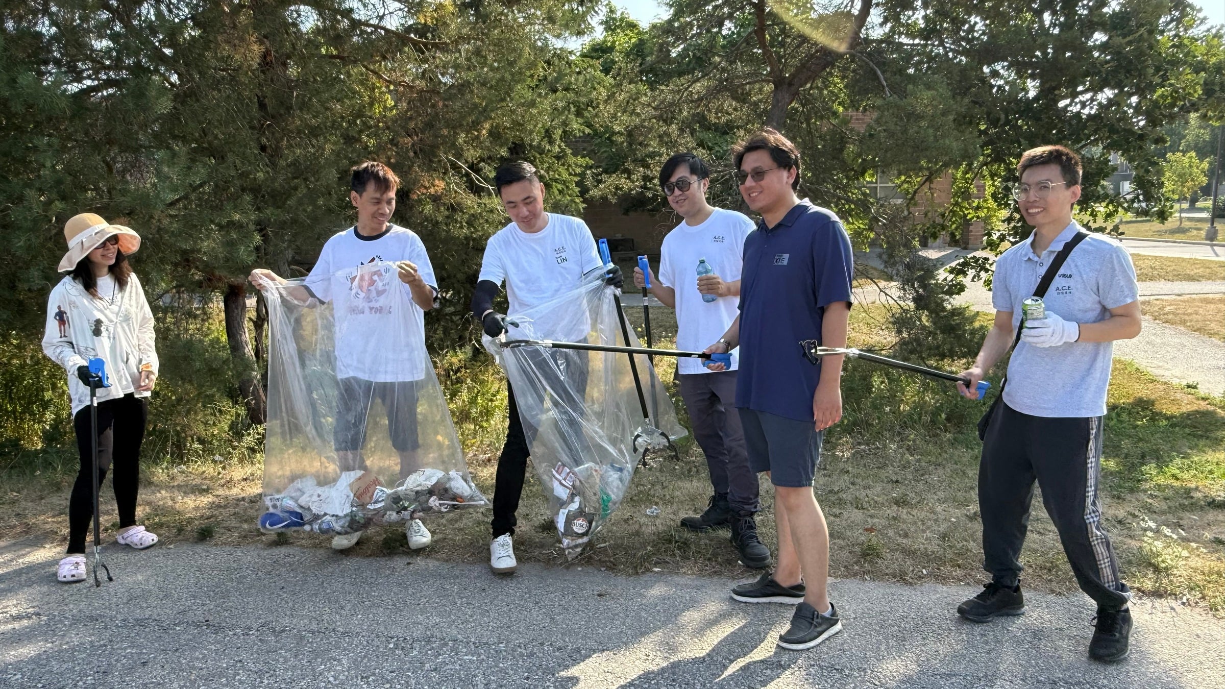 Young ACE volunteers with litter bags and grabbers on a park path